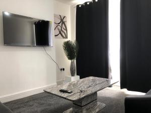 a living room with a table and a tv on the wall at Immaculate 3-Bed House in Nottingham in Nottingham