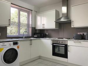 a kitchen with white cabinets and a washing machine at Immaculate 3-Bed House in Nottingham in Nottingham