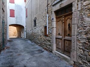 un callejón con un edificio de piedra y una puerta de madera en La Jolie Dourbie de Nant en Nant