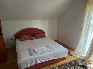 Schlafzimmer mit einem Bett mit rotem Kopfteil und Vorhängen in der Unterkunft Milovan in Cetinje