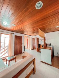 a living room with wooden ceilings and a kitchen at Arbiru Beach Resort in Dili