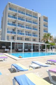 a large apartment building with a pool and lounge chairs at Yasmin Hotel in Ayvalık