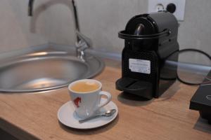 une tasse de café assise sur un comptoir avec une caméra dans l'établissement Apartman De Lux - Cacak, à Čačak