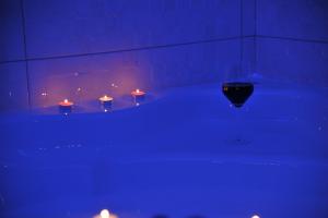 d'une baignoire avec bougies et lumières bleues. dans l'établissement Apartman De Lux - Cacak, à Čačak