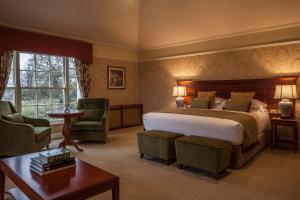 1 Schlafzimmer mit einem Bett, 2 Stühlen und einem Tisch in der Unterkunft Leixlip Manor Hotel in Leixlip