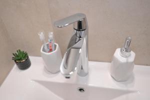 - un lavabo avec un robinet et des brosses à dents dans l'établissement Apartman De Lux - Cacak, à Čačak