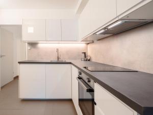 cocina con armarios blancos y encimera negra en SKY9 Apartments Stadthalle, en Viena