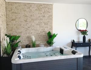 bañera en una habitación con pared de ladrillo en Évasion avec jacuzzi intérieur, en Rosières-près-Troyes