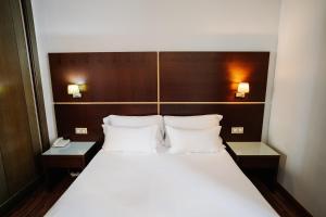 ブルゴスにあるパラシオ デ ロス ブラソネス スイートのテーブル2台と枕2つが備わるホテルルームのベッド1台分です。