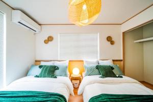 a bedroom with two beds with green and white at SHIOYA STAY in Okinawa City