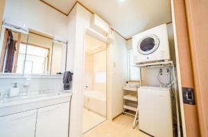 una pequeña cocina con fregadero y microondas en SHIOYA STAY en Okinawa City