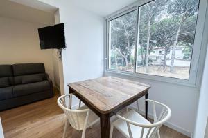 een woonkamer met een tafel en stoelen en een raam bij T2D - Best place in Cala-Montgo beach Apartment 2 Beds, Air Conditioning and private Parking in L'Escala