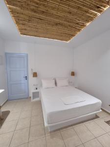 a bedroom with a white bed and a wooden ceiling at Ilias Place in Ios Chora