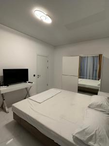 a white bedroom with a large bed and a desk at Koya Tower by Lake Mamaia in Mamaia