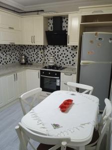 eine Küche mit einem weißen Tisch und einem weißen Kühlschrank in der Unterkunft Deniz manzaralı lüks daire in Uğurlu