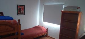 サンタ・ロサ・デ・カラムチタにあるCabañas Lo de Albertoのベッドルーム1室(ベッド1台付)、ドレッサー(赤いベンチ付)
