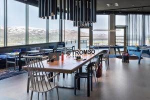 un restaurante con mesa, sillas y ventanas en Moxy Tromso, en Tromsø