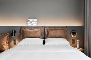 ein Schlafzimmer mit einem großen Bett mit weißer Bettwäsche und braunen Kissen in der Unterkunft Moxy Tromso in Tromsø