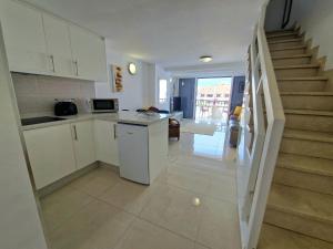 a kitchen with white cabinets and a staircase at Parque Santiago 1 F-348 by TENERIFE DREAM PROPERTIES in Playa de las Americas