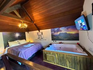 a bedroom with a bed and a tub and a tv at Recanto Lira I in Monte Verde