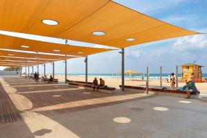 a boardwalk with people sitting on benches on the beach at דירת 2 חדרים בטיילת בת ים in Bat Yam