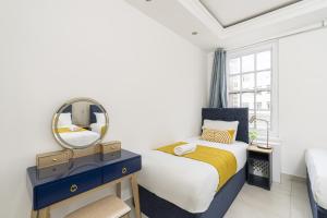 - une chambre avec un lit et un miroir dans l'établissement Marble Arch Apartments, à Londres