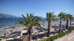 una playa con palmeras, sombrillas y el océano en Bono Residence, en Marmaris