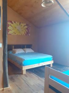 1 dormitorio con 1 cama con sábanas azules y una pintura en la pared en Sons do Eo Apartamentos Turísticos, en Baleira