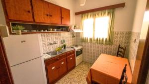 a small kitchen with a white refrigerator and a table at Elsono Apartments Νο 2 - Aegina in Aegina Town