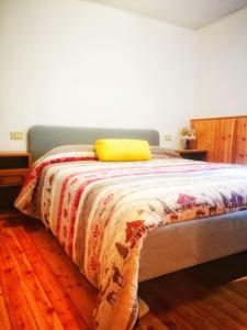 a bed with a yellow pillow on top of it at Cozy Alpine House di Svaizer in San Martino di Castrozza
