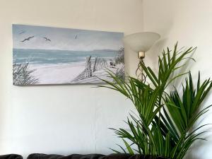 a painting hanging on a wall next to a plant at The KinBrae Apartment in Torquay