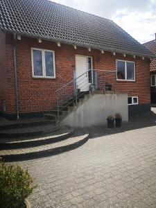 - un bâtiment en briques avec des escaliers menant à une porte dans l'établissement Helle´s casa, à Herning