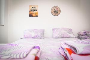 a bed with pink sheets and a clock on the wall at Marko Polo Apartment in Sarajevo