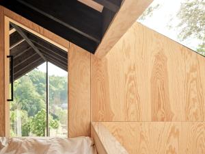 ein Schlafzimmer mit einer Holzwand und einem Fenster in der Unterkunft Hutstuf The Beaver & Private Outdoor Spa in La-Roche-en-Ardenne