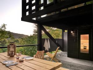 einen Holztisch und Stühle auf einer Terrasse in der Unterkunft Hutstuf The Beaver & Private Outdoor Spa in La-Roche-en-Ardenne