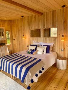 a large bed in a room with wooden walls at LES CABANES DE LUTINA 