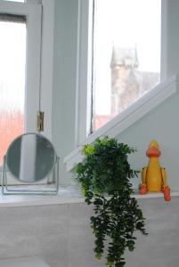 a bathroom with a mirror and a plant next to a window at Auld Fishers Hoist- traditional home by the sea in Anstruther