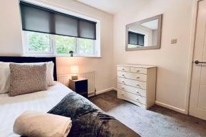 a bedroom with a bed and a dresser and a mirror at Urban Bliss Stylish Townhouse with Free Parking for a Convenient City Stay in Liverpool