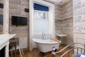 a bathroom with a tub and a sink and a tv at Bower House in London