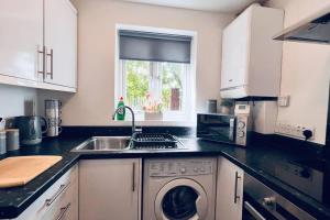 a kitchen with a sink and a washing machine at Urban Bliss Stylish Townhouse with Free Parking for a Convenient City Stay in Liverpool