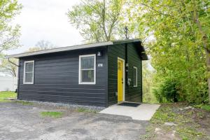 a black tiny house with a yellow door at Campfire Cottage Fireplace, fire pit & no chores! in Kingston