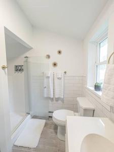 La salle de bains blanche est pourvue de toilettes et d'un lavabo. dans l'établissement Campfire Cottage Fireplace, fire pit & no chores!, à Kingston
