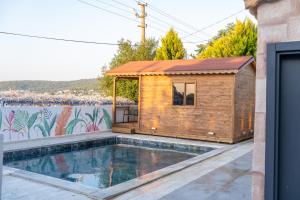 a tiny house with a swimming pool next to a wall at Akyalı Boutique Hotel in Guvercinlik