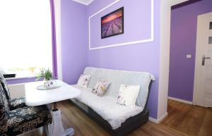 a purple living room with a couch and a table at Apartament Lawendowy in Wałbrzych