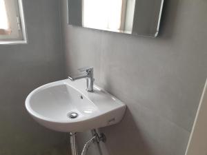 ein weißes Waschbecken im Bad mit Spiegel in der Unterkunft Κεντρικό στούντιο 250m σχεδόν από την παράλια. in Volos