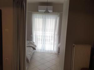 a bedroom with a bed and a large window at Κεντρικό στούντιο 250m σχεδόν από την παράλια. in Volos