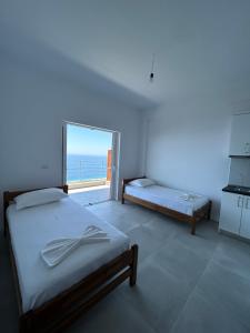 sypialnia z 2 łóżkami i dużym oknem w obiekcie Vila Jona w mieście Palasë