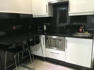 cocina con armarios blancos y encimera negra en Paddington Apartments, en Londres