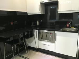 eine Küche mit weißen Schränken und einer schwarzen Arbeitsplatte in der Unterkunft Paddington Apartments in London + 8 Fotos