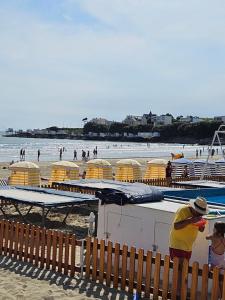 Un homme debout sur une plage avec des gens dans l'eau dans l'établissement Appartement de charme , Royan, proche mer avec balcon., à Royan